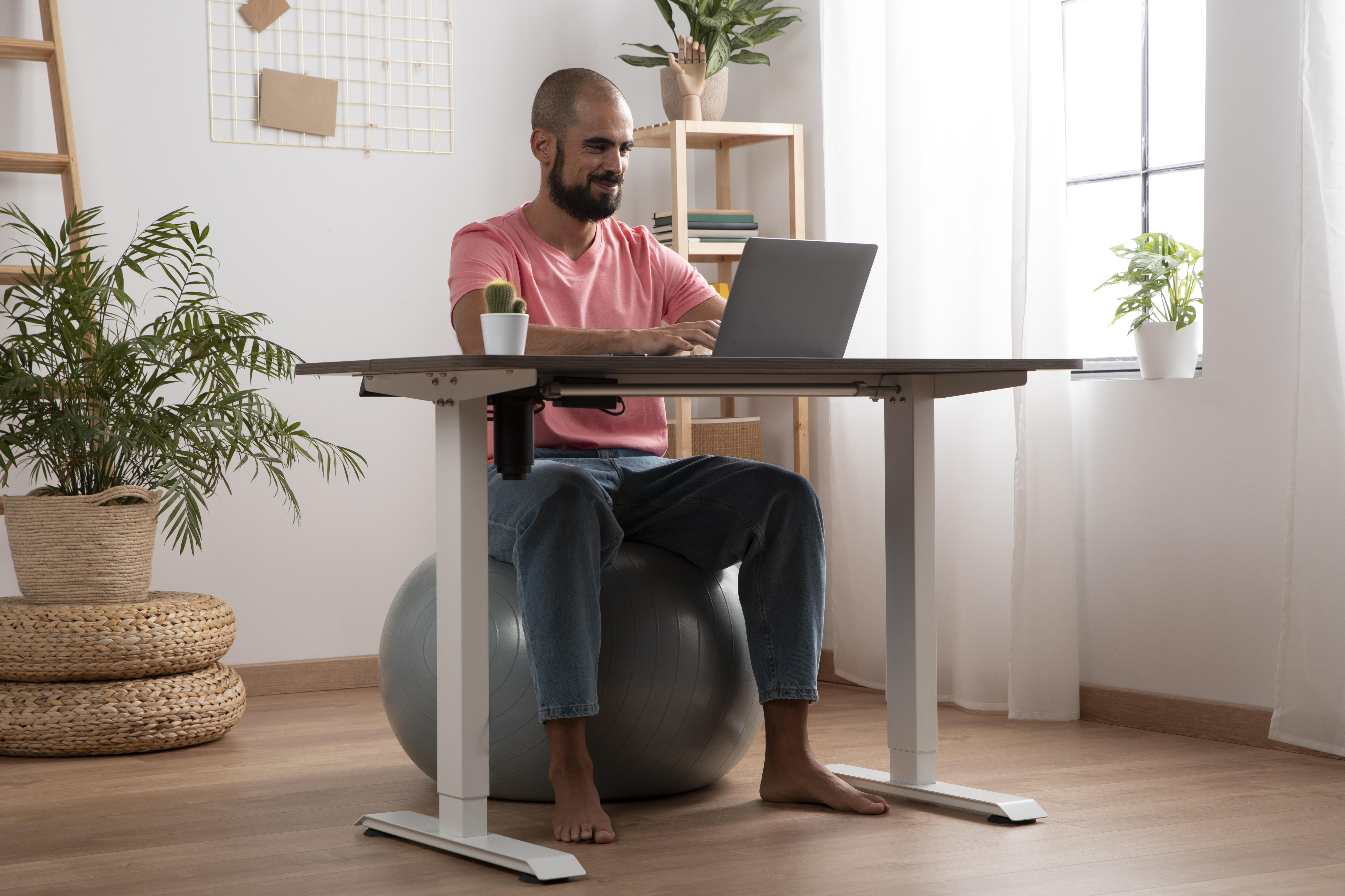 Man sitting on physio ball whilst using a computer at a desk